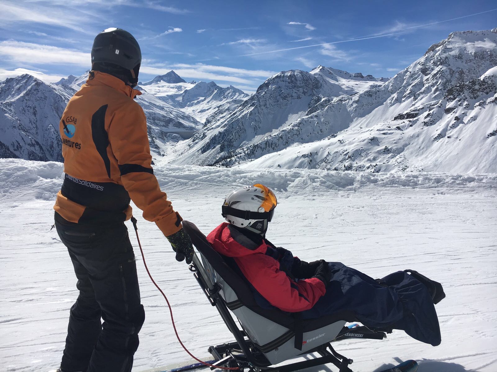 Un skieur assis et son accompagnant devant les montagnes enneigées